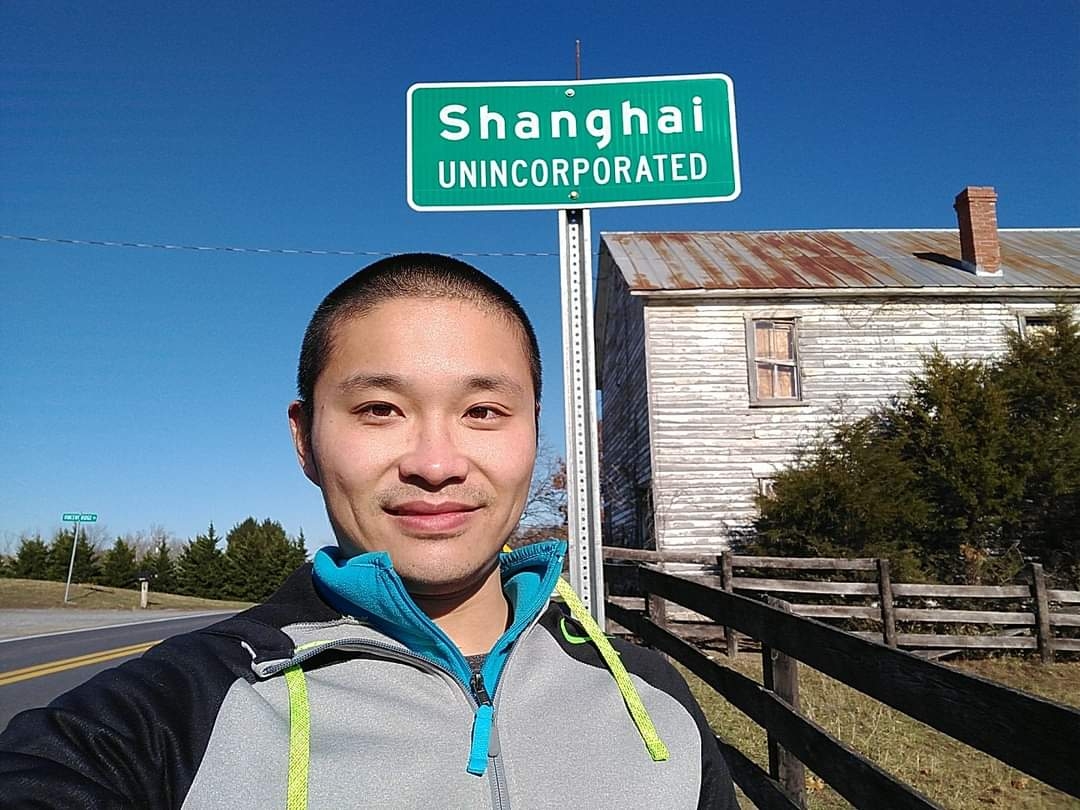 selfie in front of a sign "Shanghai unincorporated"